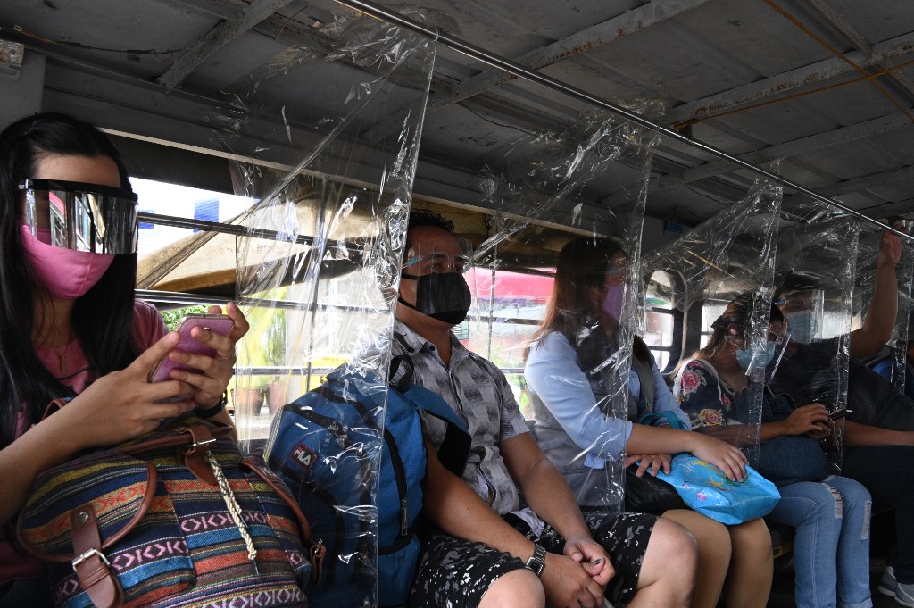 In this photo taken on September 8, 2020, passengers wearing face shields sit next to plastic dividers, as part of health protocols imposed by authorities on passenger jeepneys against the COVID-19 coronavirus in Manila. - Many face the new normal in the Philippines, where it is now compulsory to wear both face masks and plastic shields in indoor public spaces and on public transport to curb the spread of the COVID-19 coronavirus. (Photo by Ted ALJIBE / AFP) / TO GO WITH Health-virus-Philippines,PHOTOESSAY