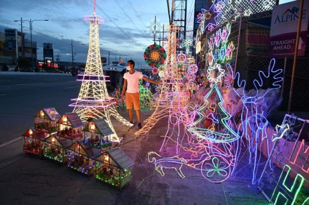 This photo taken on October 6, 2020 shows a worker standing beside lanterns and lit ornaments, including several shaped in the likeness of the Eiffel Tower, for sale during the festive season at a shop in San Fernando town in Pampanga province. - The Philippines boasts one of the world's longest Christmas seasons, kicking off in September with fairy lights and artificial trees decorating malls, festive tunes on the radio and party-packed calendars. But the coronavirus pandemic looks set to be the grinch that spoils the four-month-long celebration this year. (Photo by Ted ALJIBE / AFP) / TO GO WITH AFP STORY: HEALTH-VIRUS-PHILIPPINES-TRADITION-CHRISTMAS, FOCUS BY CECIL MORELLA  MANILA, Philippines — The Philippine National Police (PNP) has urged event organizers and bazaar stall owners who would set up programs this holiday season to coordinate with local government units (LGUs) so that health protocols against COVID-19 would be followed.  In a statement on Tuesday, PNP chief Gen. Guillermo Eleazar said that while the police force is doing its best to manage crowds in public spaces during the incoming Christmas season, organizers must do their share in minimizing the risks of COVID-19 transmissions.  “I would advise organizers of tiangges or bazaars to work with LGUs to ensure that participants in their activities strictly observe [minimum public health and safety] protocols, particularly physical distancing,” Eleazar said.  “Mahalaga lalo ang pagsunod sa health protocols partikular na ang physical distancing kung may kinalaman sa pagkain ang event, maski al fresco dining, dahil kinakailangan ditong mag-alis ng face mask,” he added.  (It is important to follow health protocols, particularly physical distancing, if an event would involve dining, even if that is alfresco dining because you need to remove your face masks.)  For the nth time, Eleazar reminded the public to remain on guard against COVID-19 as the battle against the pandemic is not yet over despite constantly decreasing numbers across the country.  The PNP chief asked Filipinos to avoid being complacent, especially if they visit areas of public convergence or shops frequented by huge crowds like the Divisoria market in Manila — as seeking savings may even result in huge expenses due to medications.  “Huwag sana tayo magpakakumpiyansa sa pamimili sa Divisoria o sa mga tiangge lalo’t siksikan. Baka ang mangyari ay nakapamili nga tayo ng mura ay mapapagastos naman tayo ng malaki sa pagpapagamot,” Eleazar stressed.  (Let us not be too complacent in buying goods like in Divisoria or bazaars, especially when huge crowds are present.  Because what may happen is that while you can buy cheaper goods, you may spend more on your medication.)  “Pinapaalala ko sa ating mga kababayan na ang kaunting pagluwag sa mga panuntunan ay hindi nangangahulugang wala na ang banta ng COVID-19 at wala na rin ang panganib na dumami muli ang mga kaso.  Kailangang magtulungan tayo para mapanatili o mas mapababa pa ang mga naitatalang COVID-19 cases,” he added.  (I am reminding our fellow Filipinos that the easing of quarantine restrictions does not mean there is no COVID-19 threat and there are no dangers if cases increase once again.  We must help each other in maintaining lower infection numbers.)  Most areas in the country, including Metro Manila, are seeing lower COVID-19 cases, after the surge caused by the Delta variant last August and September.  However, several government officials, including Eleazar, warned against being too relaxed as the pandemic threat and newly discovered subvariants are still present.  In recent weeks, authorities have seen an influx of crowds in public areas like Quirino Grandstand, malls, and the infamous dolomite beach at Manila Bay.  In response to crowding, Eleazar has already directed police offices to monitor whether there is a need to augment the personnel deployed.  READ: PNP pleads to public: Play your part, follow safety protocols while on holidays   READ: PNP deploys more cops to impose health protocols in Manila’s ‘white sand beach’   As of Monday, the country still has 43,185 active COVID-19 infections due to 3,117 new cases.  However, the daily increase in cases and the active case count are far from the numbers during the August and September surge.  READ: PH records 3,117 new COVID-19 cases, lowest since May 23 