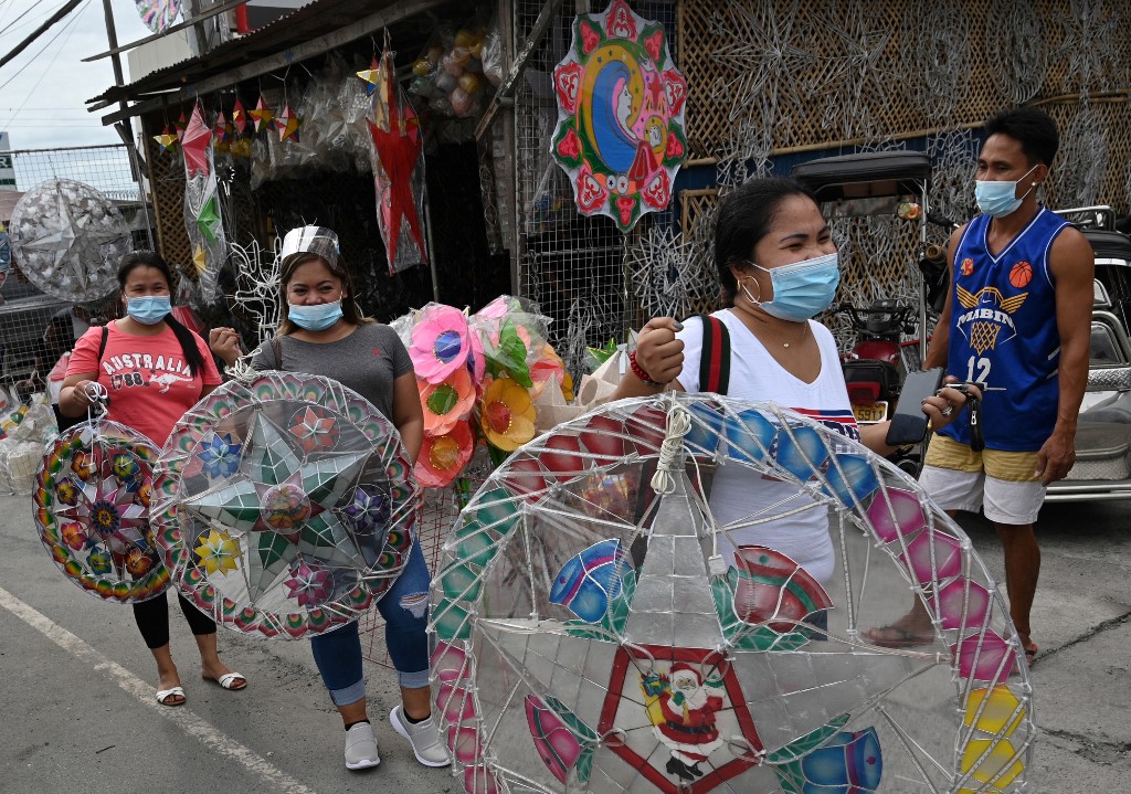 This photo taken on October 6, 2020 shows customers walking away with newly-purchased lanterns for the festive season in San Fernando town in Pampanga province. - The Philippines boasts one of the world's longest Christmas seasons, kicking off in September with fairy lights and artificial trees decorating malls, festive tunes on the radio and party-packed calendars. But the coronavirus pandemic looks set to be the grinch that spoils the four-month-long celebration this year. (Photo by Ted ALJIBE / AFP) / TO GO WITH AFP STORY: HEALTH-VIRUS-PHILIPPINES-TRADITION-CHRISTMAS, FOCUS BY CECIL MORELLA