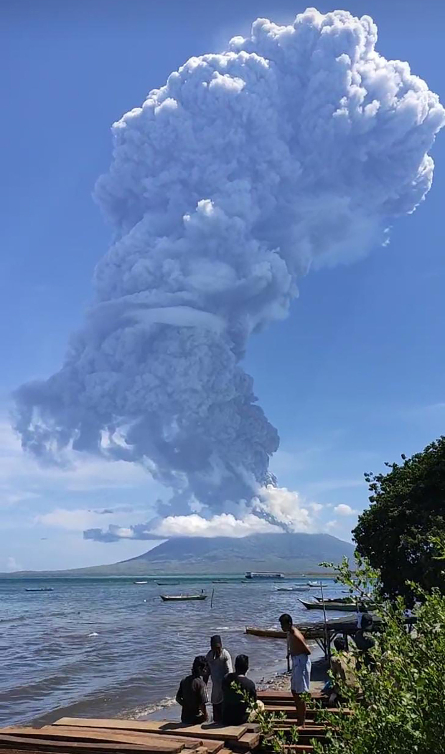 Residents gather to watch as Mount Ili Lewotolok spews ash during a volcanic eruption in Lembata, East Nusa Tenggara on November 29, 2020. (Photo by JOY CHRISTIAN / AFP)