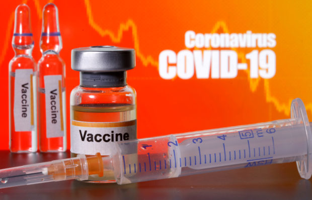 FILE PHOTO: Small bottles labelled with "Vaccine" stickers stand near a medical syringe in front of displayed "Coronavirus COVID-19" words in this illustration taken April 10, 2020. REUTERS/Dado Ruvic/Illustration