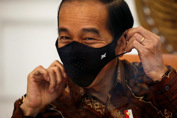Indonesian President Joko Widodo reacts as he wears a protective mask during an interview with Reuters at the Presidential Palace in Jakarta