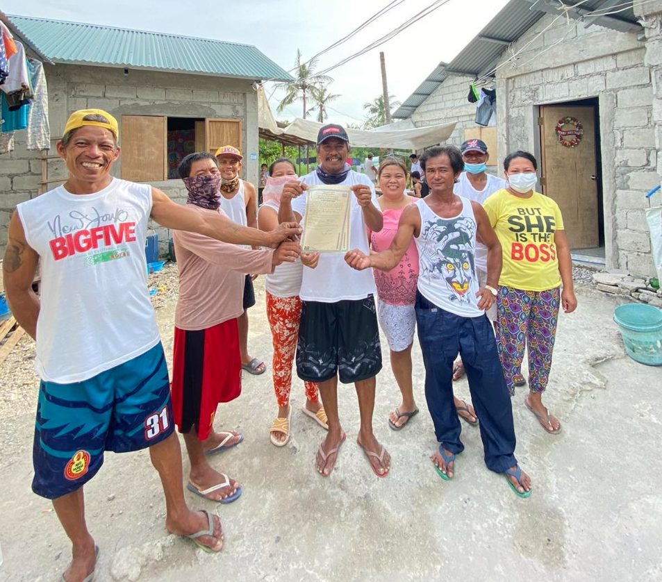 Teody Bacon and other former residents of Sitio Kinse hold the land ownership title to their new homes in Barangay Bambang in Bulakan.