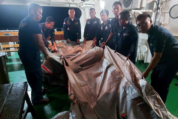 Officers of an Indonesian Coast and Sea Guard (KPLP) patrol ship hold suspected remains of an emergency ladder of the Sriwijaya Air plane flight SJ182, which crashed into the sea near Jakarta