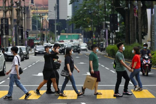 Malaysians wearing face masks crossing a street