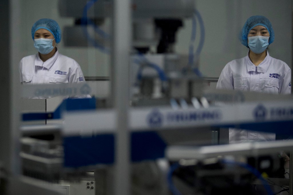 Workers are seen at Sinopharm’s packaging workshop for the  inactivated SARS-Cov-2 vaccine in Sinopharm’s headquarters in Beijing during a media tour organized by the State Council Information Office (SCIO) on February 26, 2021. (Photo by Noel Celis / AFP)