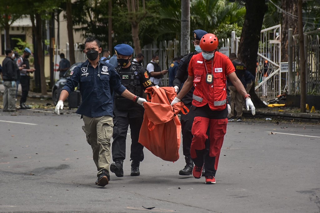 Indonesian police carry a bag with the remains of a suspected suicide bomber after an explosion outside a church in Makassar on March 28, 2021. (Photo by INDRA ABRIYANTO / AFP)