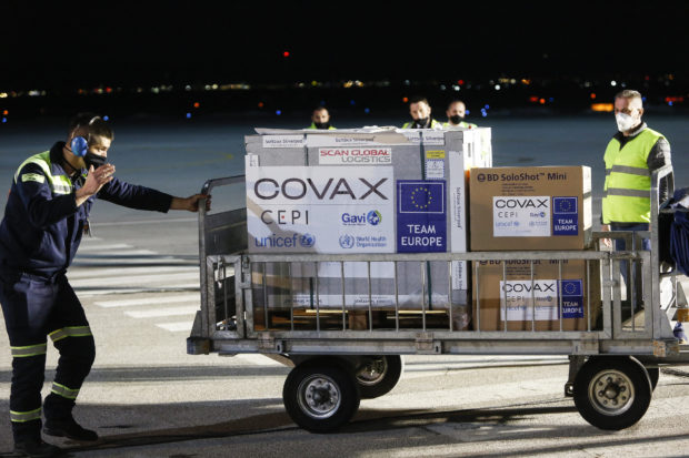 Airport employees push a cart carrying first shipment of Covid-19 jabs at the Pristina International Airport on March 28, 2021. - Kosovo received on March 28, 2021 its first shipment of Covid-19 jabs which were delivered through the UN-backed Covax scheme to help poorer nations that had delays in reaching Balkan nations. The batch of 24,000 doses of the AstraZeneca/Oxford vaccine was delivered as Kosovo, like the rest of its Balkans neighbours, is fighting a significant surge in the number of coronavirus infections. (Photo by - / AFP)