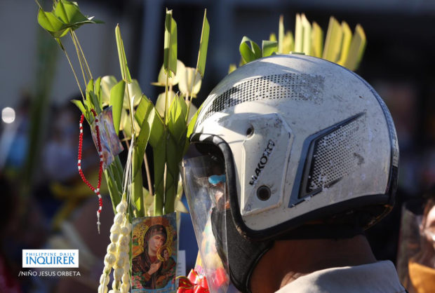 Motorcycle rider carrying palm fronts on Palm Sunday. STORY: Only vaccinated persons can enter places of worship – Año