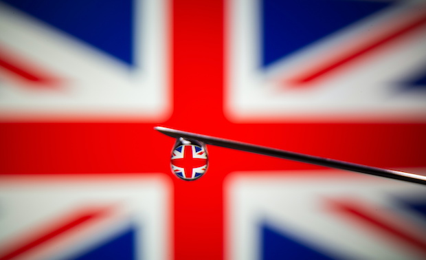 UK flag is reflected in a drop on a syringe needle in this illustration photo