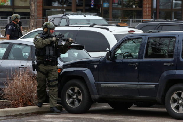 Law enforcement officers stand at the perimeter of a shooting site at King Soopers grocery store in Boulder