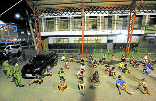 LONG NIGHT Policemen apprehended 1,499 residents and fined 1,588 others in Metro Manila, including the 27 adults and 11 minors seen here at a covered court in Binondo, Manila, for staying out on Monday night in violation of the 10 p.m. to 5 a.m. curfew. —LYN RILLON
