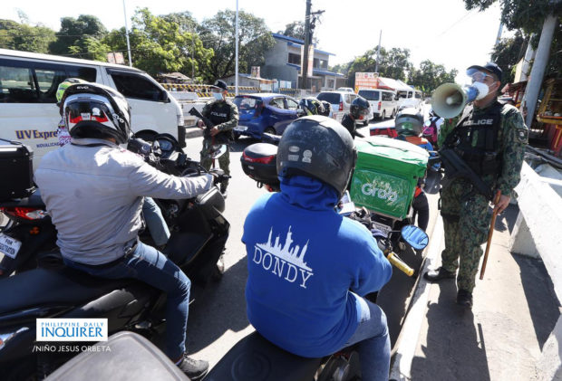 Policemen check identification cards of motorists at a checkpoint passing the border of San Jose Del Monte, Bulacan-Caloocan City on Monday, March 29, 2021