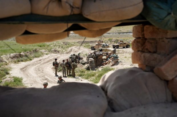 In this photo taken on June 6, 2019, US troops are seen through a firing position at the Afghan National Army (ANA) checkpoint in Nerkh district of Wardak province west of Kabul. - A skinny tangle of razor wire snakes across the entrance to the Afghan army checkpoint, the only obvious barrier separating the soldiers inside from any Taliban fighters that might be nearby.