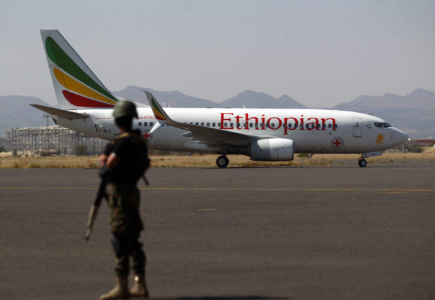 A Yemeni soldier guards an Ethiopian Airlines Boeing 737-760 aircraft used by International Red Cross, carrying prisoners who were held by the Saudi-backed government side on the tarmac of an airport in Yemen's Huthi rebels-held capital Sanaa on October 15, 2020, as the war-torn country began swapping 1,000 prisoners in a complex operation overseen by the International Committee of the Red Cross. - The exchange, agreed after a week of negotiations in Switzerland last month, involves the release of 1,081 prisoners over two days, the largest number since the conflict erupted in 2014.