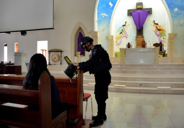 A policeman inspects the premises of the Santo Fransiscus Xaverius church ahead of religious services on Good Friday in Kuta, near Denpasar on Indonesia's resort island of Bali, on April 2, 2021