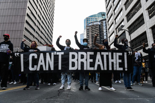 In this file photo demonstrators hold a banner during the “I Can’t Breathe - Silent March for Justice” in front of the Hennepin County Government Center on March 7, 2021, where the trial of former Minneapolis police officer Derek Chauvin, charged with murdering African American man George Floyd, will begin on March 8, 2021, in Minneapolis, Minnesota. - A respiratory doctor testified on April 8, 2021 that George Floyd died from a lack of oxygen and that police officer Derek Chauvin's knee was on his neck almost all the time he was facedown in the street with his hands cuffed behind his back. Martin Tobin, a pulmonologist, told the jury at Chauvin's murder and manslaughter trial that he had watched videos of Floyd's May 25, 2020 arrest "hundreds of times.""Mr. Floyd died from a low level of oxygen," Tobin told the nine-woman, five-man jury hearing the high-profile case in a heavily guarded Minneapolis courtroom. (Photo by CHANDAN KHANNA / AFP)