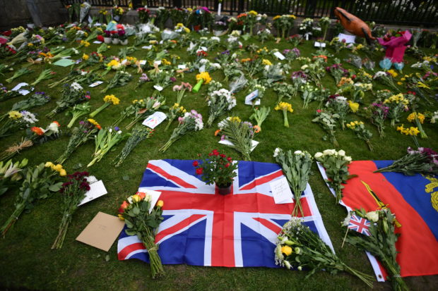 A Union Flag is laid with floral tributes outside Windsor Castle, in Windsor, west of London, on April 9, 2021, following the announcement of the death of Britain's Prince Philip, Duke of Edinburgh. - Queen Elizabeth II's husband Prince Philip, who recently spent more than a month in hospital and underwent a heart procedure, died on April 9, 2021, Buckingham Palace announced. He was 99. (Photo by Ben STANSALL / AFP)