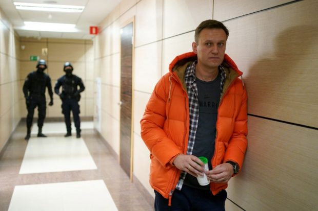 In this file photo taken on December 26, 2019 Russian opposition leader Alexei Navalny stands near law enforcement agents in a hallway of a business centre, which houses the office of his Anti-Corruption Foundation (FBK), in Moscow. - Russian prosecutors on April 16, 2021 asked a Moscow court to designate the network of regional offices of jailed Kremlin critic Alexei Navalny and his Anti-Corruption Foundation (FBK) as "extremist organisations". 