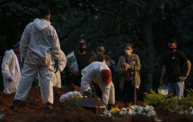 People mourn as a relative is buried by cemetery workers in protective gear as a preventive measure against the spread of the novel coronavirus disease, COVID-19, at the Vila Formosa cemetery in Sao Paulo, Brazil, on April 17, 2021. - The number of people who have died worldwide in the Covid-19 pandemic has surpassed three million. The worlds Covid-19 death toll surpassed three million on Saturday, according to Johns Hopkins University. 