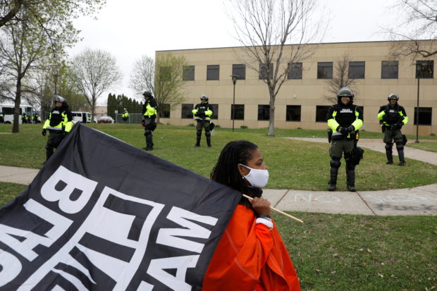 An activist paces in front of officers at the Brooklyn Center Police Department after an officer-involved killing of Daunte Wright, 20, following a traffic stop in Brooklyn Center, Minnesota, U.S., April 12, 2021. REUTERS/Nicholas Pfosi