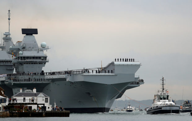Royal Navy aircraft carrier, HMS Queen Elizabeth, is towed by tugs as it arrives at Portsmouth Naval base, Britain August 16, 2017