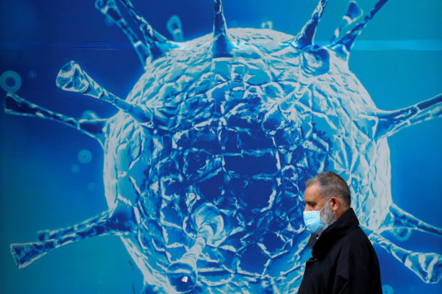 A man wearing a protective face mask walks past an illustration of a virus outside a regional science centre amid the coronavirus disease (COVID-19) outbreak, in Oldham, Britain August 3, 2020. REUTERS/Phil Noble/File Photo