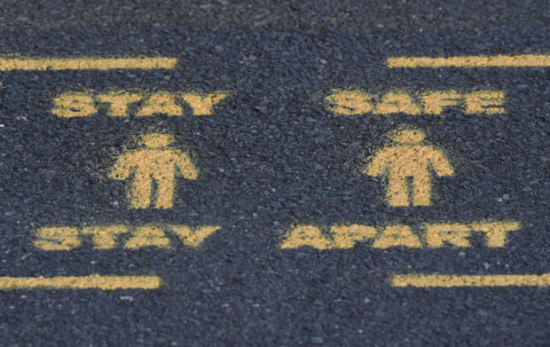 Public health signs are seen sprayed on a pavement, whilst the reproduction "R" number of COVID-19 infections in the United Kingdom has risen and may be above 1, the Government Office for Science said on Friday, indicating a risk that the overall epidemic is growing, London, Britain, September 11, 2020