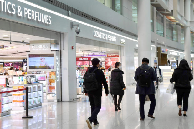 Passengers walk past duty free stores in Terminal 1 at Incheon Airport