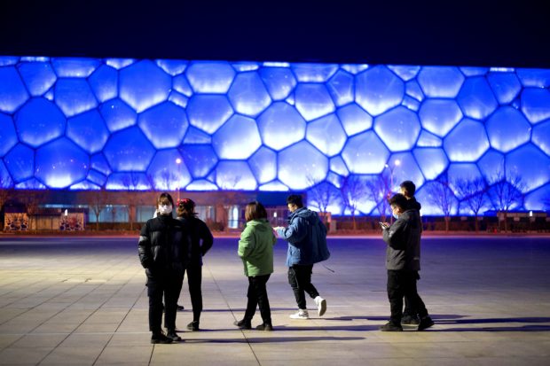 People walk in front of the National Aquatics Center, known as the Water Cube which will become the Ice Cube when it serves as the venue for the curling competition at the 2022 Winter Olympics, in Beijing on February 4, 2021, a year before the opening of the Games on February 4, 2022.
