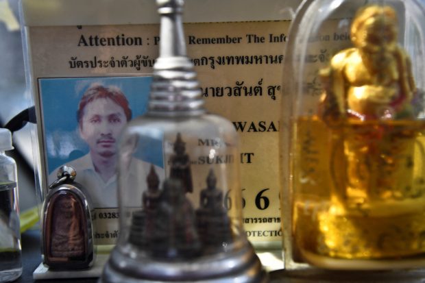 This photo taken on March 3, 2021 shows taxi driver Wasan Sukjit's official taxi identification card behind some of his protective Buddhist figurines in Bangkok. - Buddhist-majority Thailand has a deeply superstitious culture as much of the population steeped in the belief that luck and good fortune can be accrued through blessed objects -- with many taxi drivers buoyed by the peace of mind the rituals gives them against the spread of the Covid-19 coronavirus. (Photo by Lillian SUWANRUMPHA / AFP) / To go with THAILAND-HEALTH-VIRUS-RELIGION-SUPERSTITION,FOCUS by Pitcha DANGPRASITH