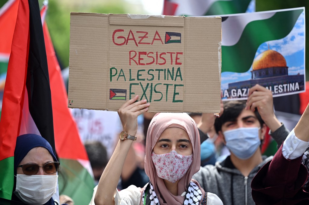 A woman holds up a sign reading "Gaza resists. Palestine exists" during a demonstration marking the 73rd anniversary of the "Naqba" (catastrophe) in Madrid on May 15, 2021. - The "Naqba", (Day of Catastrophe) refers to the day May 15, 1948, when the modern state of Israel was established following the Arab-Israeli war, which led to the displacement of hundreds of thousands of Palestinian people. (Photo by GABRIEL BOUYS / AFP) / The erroneous mention[s] appearing in the Object Name of this photo by GABRIEL BOUYS has been modified in AFP systems in the following manner: [PALESTINIAN] instead of [PALESTINE]. Please immediately remove the erroneous mention[s] from all your online services and delete it (them) from your servers. If you have been authorized by AFP to distribute it (them) to third parties, please ensure that the same actions are carried out by them. Failure to promptly comply with these instructions will entail liability on your part for any continued or post notification usage. Therefore we thank you very much for all your attention and prompt action. We are sorry for the inconvenience this notification may cause and remain at your disposal for any further information you may require.