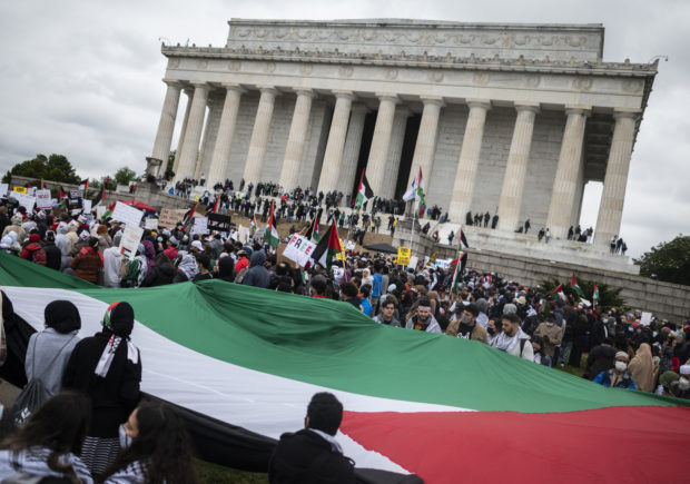 Supporters of Palestine gather around a Palestine flag as they hold a rally at the Lincoln Memorial in Washington, DC on May 29, 2021. - More than 1,000 rallied Saturday in Washington in support of  Palestinians and calling for an end to US aid to Israel. The demonstration on the steps of the Lincoln Memorial came as a ceasefire that ended 11 days of intense fighting between Israel and the Islamist movement Hamas in the Gaza Strip has so far held. (Photo by ANDREW CABALLERO-REYNOL