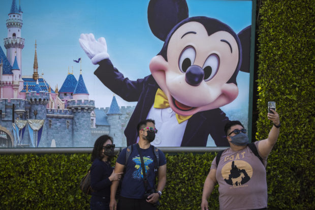 ANAHEIM, CA - APRIL 30: People pose for selfies at Disneyland Park as it reopens for the first time since the COVID 19 pandemic forced the park to shut down last year on April 30, 2021 in Anaheim, California. California saw some of the highest infection rates in the nation over the winter but now enjoys some of the lowest. Los Angeles County, for example, is now expected to move from the orange tier of the states economic reopening system based on COVID-19 metrics to the least restrictive yellow tier, which would allow greater reopening freedoms, as early as next week.   David McNew/Getty Images/AFP (Photo by DAVID MCNEW / GETTY IMAGES NORTH AMERICA / Getty Images via AFP)