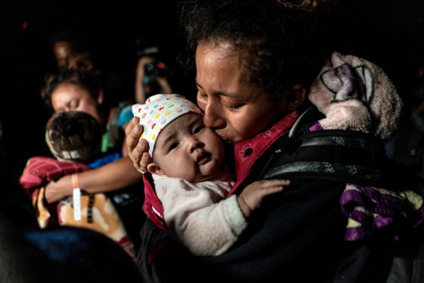 Ceidy, an asylum-seeking migrant mother from Guatemala, kisses her 3-month-old baby Bridget while waiting to be escorted by the U.S. Border Patrol agents after crossing the Rio Grande river into the United States from Mexico in Roma, Texas, U.S. April 7, 2021. Picture taken April 7, 2021
