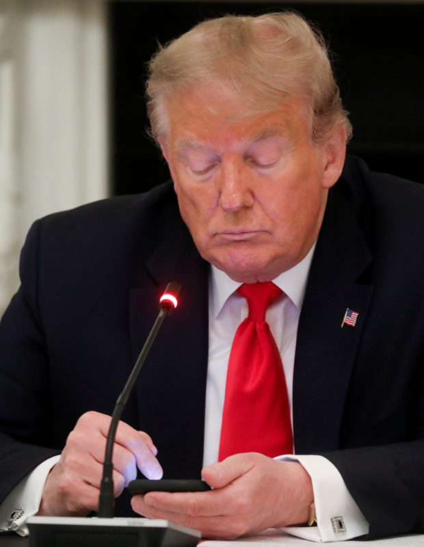 U.S. President Donald Trump taps the screen on a mobile phone s in the State Dining Room at the White House in Washington, U.S., June 18, 2020. REUTERS/Leah Millis