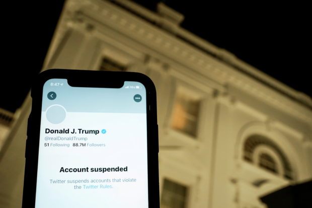  A photo illustration shows the suspended Twitter account of U.S. President Donald Trump on a smartphone and a lit window in the White House residence in Washington, U.S., January 8, 2021.  REUTERS/Joshua Roberts/Illustration