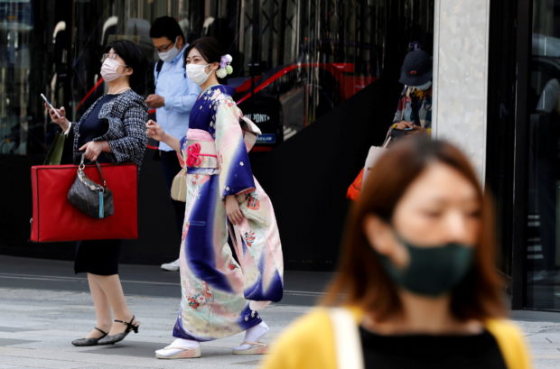 A woman in kimono clad and pedestrians wearing protective face masks, make their way at a shopping district on the first day of the country's third state of emergency, amid  the coronavirus disease (COVID-19) outbreak, in Tokyo, Japan, April 25, 2021