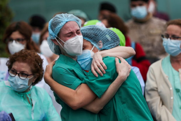 Health workers wearing protective face masks react during a tribute for their co-worker Esteban, a nurse who died of complications related to COVID-19 outside the Severo Ochoa Hospital, during the coronavirus disease (COVID-19) outbreak, in Leganes, Spain, April 13, 2020. REUTERS/Susana Vera