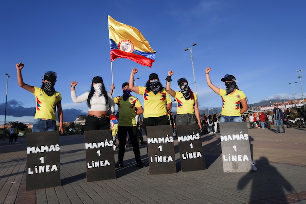 Women with protective shields that read "Mothers of the first line" pose for a photo during a protest demanding government action to tackle poverty, police violence and inequalities in healthcare and education systems, in Bogota