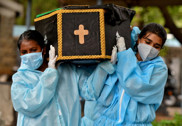 Volunteers, Akshaya (R), 22, a law student, and Esther Mary, 41, a lecturer, carry the body of a person who died from the coronavirus disease (COVID-19) for burial at a cemetery in Bengaluru, India, May 18, 2021