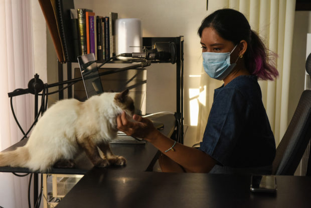 This photo taken on June 1, 2021 shows Tanya Mariano with her pet cat at her apartment in the town of San Juan, La Union province, north of Manila. - Many digital workers in congested Manila, fearing Covid-19 and fed up with lockdowns and restrictions, are escaping to largely deserted nature hotspots to do their jobs -- injecting much-needed money into communities dependent on outside visitors. (Photo by Maria Tan / AFP) / TO GO WITH AFP STORY: PHILIPPINES-HEALTH-VIRUS-LEISURE-ECONOMY, FOCUS BY ALLISON JACKSON