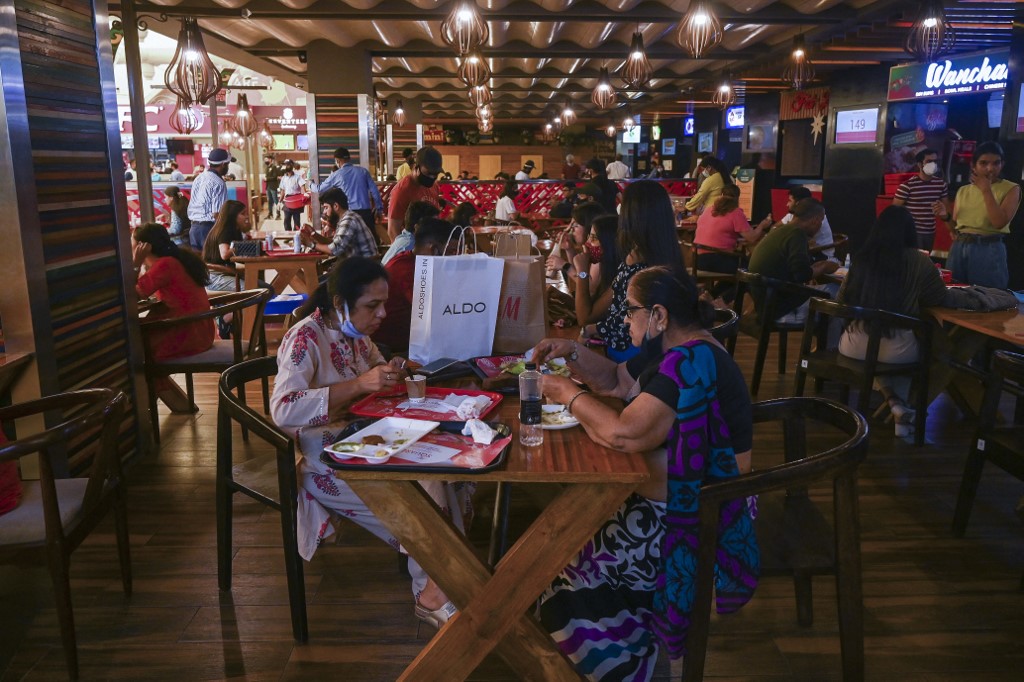 People eat a meal at a food court in Select City Mall after authorities eased a lockdown imposed as a preventive measure against the Covid-19 coronavirus, in New Delhi on June  19, 2021. (Photo by Prakash SINGH / AFP)