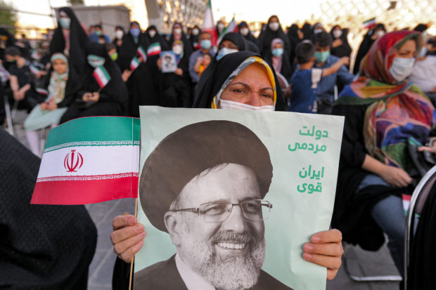 A woman holds a poster of Iran's newly-elected president Ebrahim Raisi, with text in Persian reading "government of the people, strong Iran", as supporters celebrate his victory in Imam Hussein square in the capital Tehran on June 19, 2021. (Photo by ATTA KENARE / AFP)