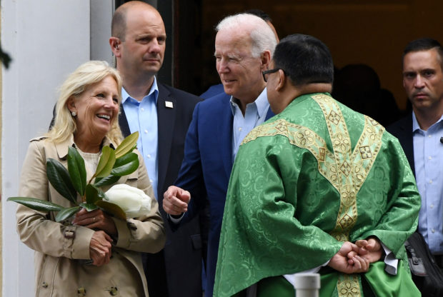 US President Joe Biden (C) and First Lady Jill Biden (L) speaks with a priest as they leave St. Joseph on the Brandywine Catholic Church in Wilmington, Delaware, June 19, 2021. - US Roman Catholic bishops issued a challenge on June 18 to President Biden over his support for abortion rights, agreeing to draft a statement on the meaning of holy communion which could potentially be used to deny the sacred rite to the US leader. (Photo by Olivier DOULIERY / AFP)