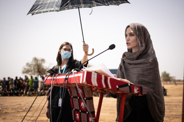 US actress Angelina Jolie, United Nations High Commissioner for Refugees (UNHCR) special envoy, gives a statement in Goudebo, a camp that welcomes more than 11,000 Malian refugees in northern Burkina Faso, on International Refugee Day on June 20, 2021. - Oscar-winning actor Angelina Jolie on Sunday visited a refugee camp in Burkina Faso sheltering thousands of Malians who have fled jihadist violence in the region. Jolie visited the camp at Goudebou, in the northeast of the landlocked west African country, as part of her role as an ambassador for the UN refugee organisation, the UNHCR. (Photo by OLYMPIA DE MAISMONT / AFP)