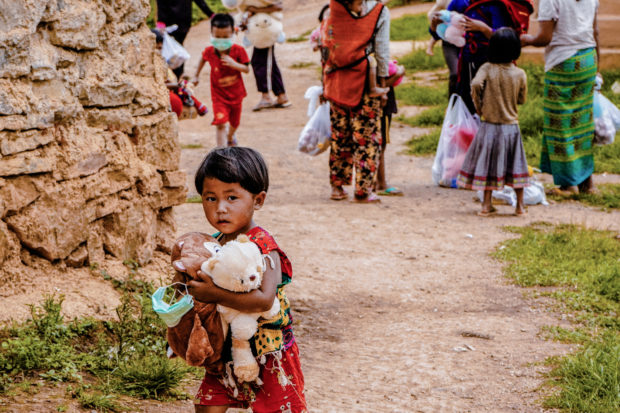In this photo taken on June 19, 2021 a child staying at a camp for people displaced during the 2015 conflict between military and an ethnic rebel group receives toys during aid distribution from a volunteer group in Lashio, in Myanmar's eastern Shan state, as their conditions have further deteriorated since the February 2021 coup. (Photo by MNWM / AFP)