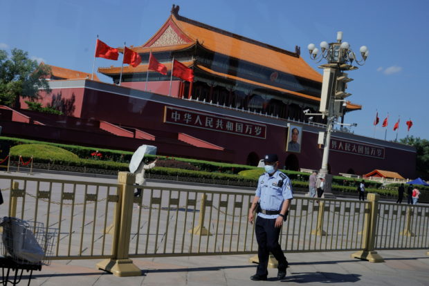 A police officer patrols in Tiananmen Square in front of a portrait of late Chinese chairman Mao Zedong in Beijing, China, June 3, 2021. Picture shot through a window.  REUTERS/Thomas Peter