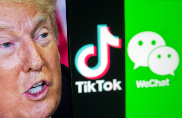 A picture of U.S. President Donald Trump is seen on a smartphone in front of displayed Tik Tok and WeChat logos in this illustration taken September 18, 2020. REUTERS/Dado Ruvic/Illustration