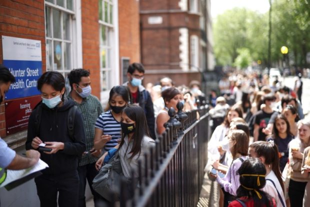 People queue outside a vaccination centre for young people and students at the Hunter Street Health Centre, amid the coronavirus disease (COVID-19) outbreak, in London